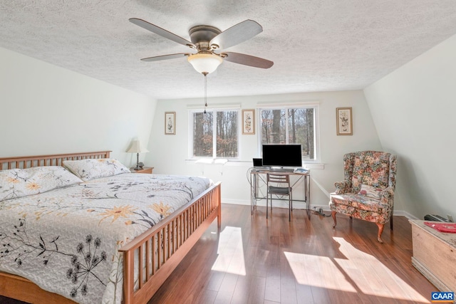 bedroom with a textured ceiling, wood finished floors, and baseboards