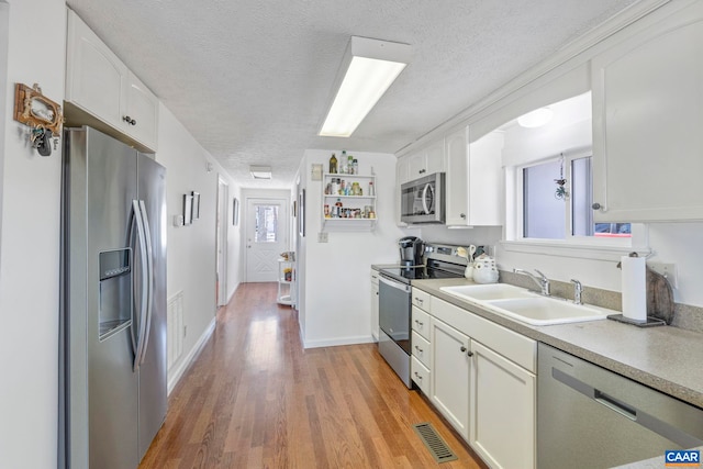 kitchen with stainless steel appliances, a sink, visible vents, and white cabinetry