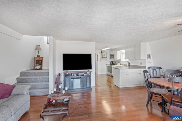 living room featuring light wood-style floors, stairs, and a textured ceiling