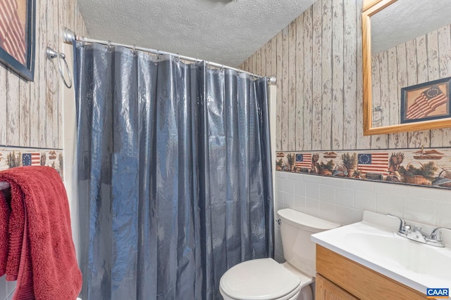 bathroom with wallpapered walls, vanity, a textured ceiling, and a wainscoted wall