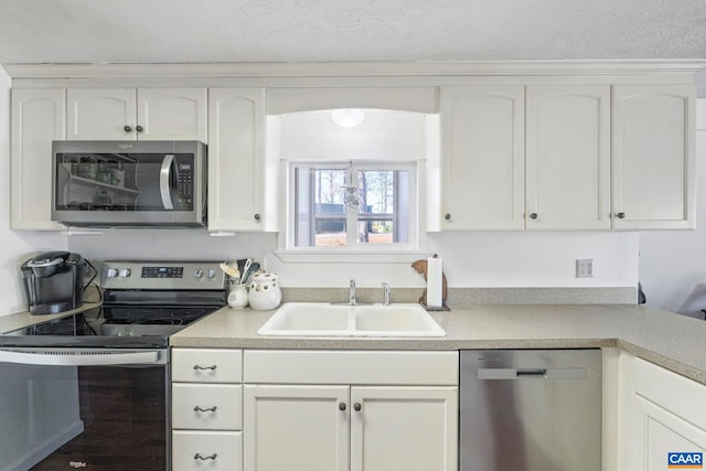 kitchen featuring white cabinetry, stainless steel appliances, a sink, and light countertops