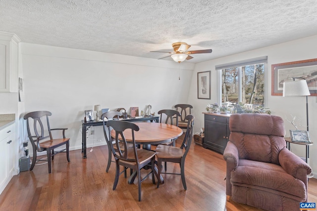 dining room with ceiling fan, a textured ceiling, dark wood finished floors, and baseboards