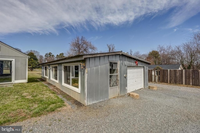 view of outdoor structure with an outbuilding, gravel driveway, and fence