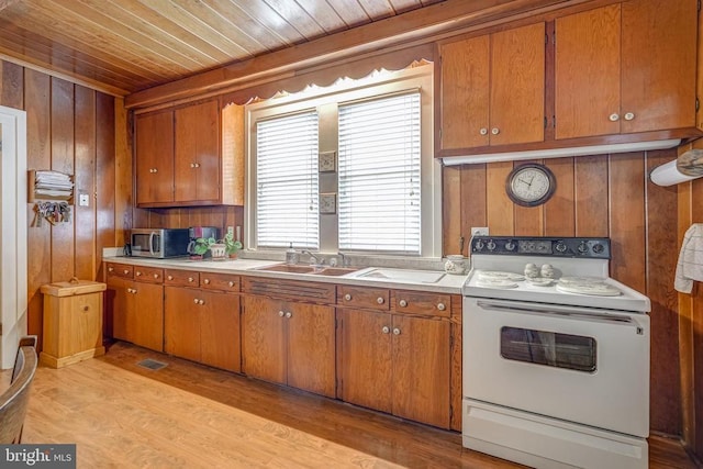 kitchen featuring stainless steel microwave, brown cabinets, and white range with electric cooktop