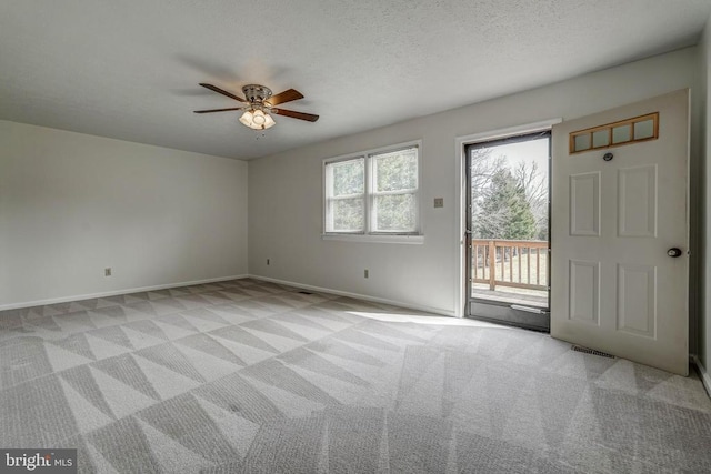 foyer entrance featuring visible vents, a ceiling fan, a textured ceiling, baseboards, and light colored carpet