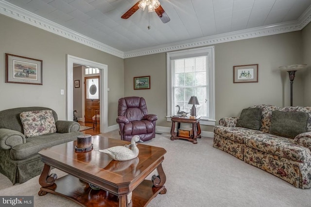 living area featuring a ceiling fan, baseboards, carpet floors, and ornamental molding