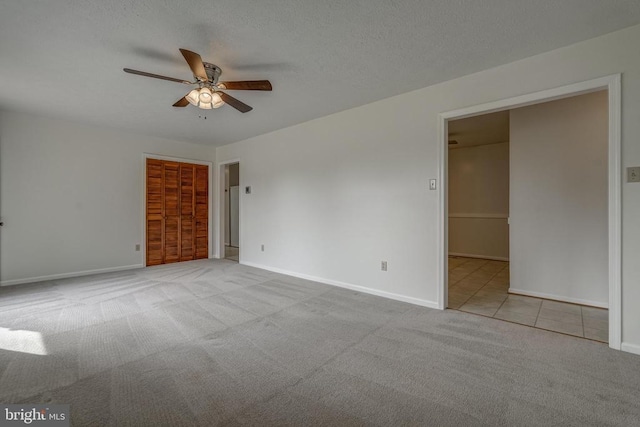 carpeted empty room featuring baseboards, a textured ceiling, ceiling fan, and tile patterned flooring