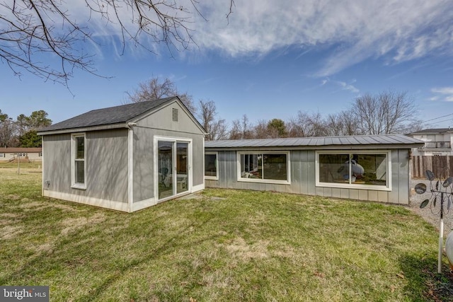 back of house featuring a yard and metal roof