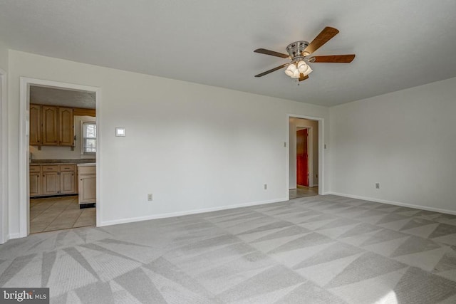 empty room with light colored carpet, baseboards, and ceiling fan