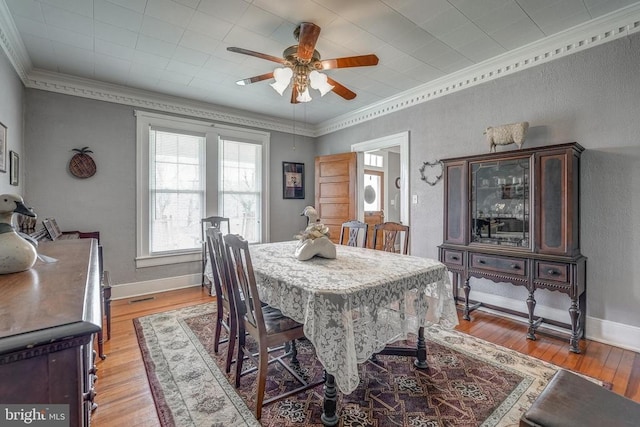 dining space featuring baseboards, light wood-style floors, a ceiling fan, and ornamental molding