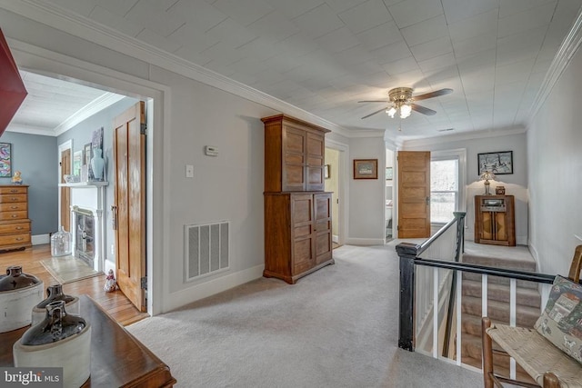 interior space with light carpet, visible vents, crown molding, and baseboards