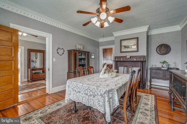 dining room with baseboards, crown molding, a ceiling fan, and wood finished floors