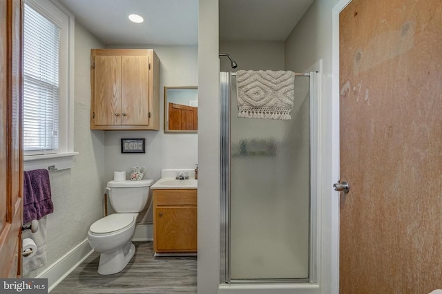 full bathroom with a shower stall, baseboards, toilet, wood finished floors, and vanity