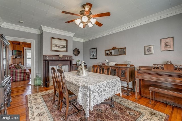 dining area featuring a ceiling fan, wood-type flooring, and ornamental molding