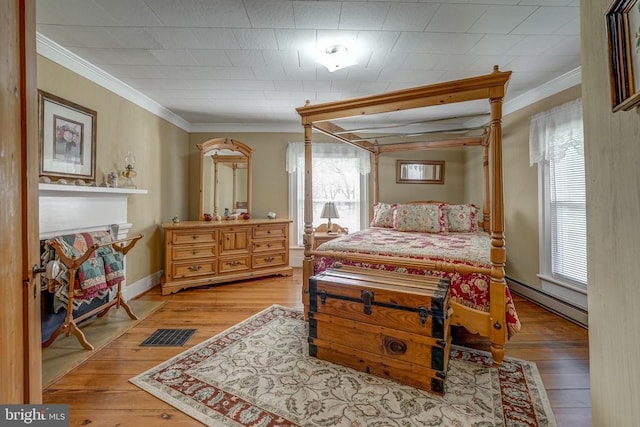 bedroom featuring a baseboard radiator, multiple windows, ornamental molding, and light wood finished floors