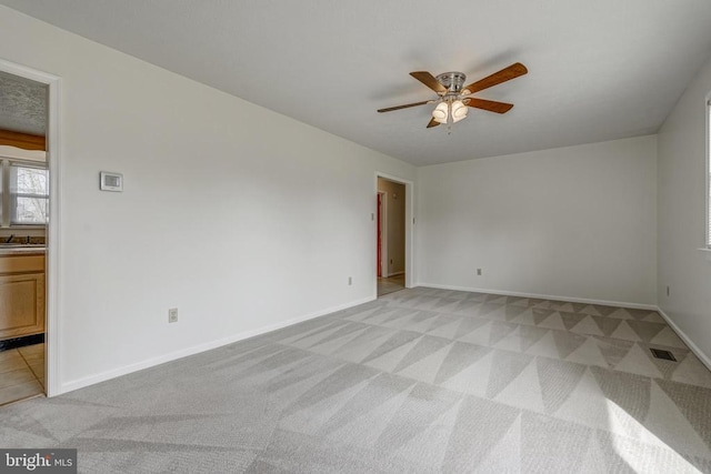 unfurnished room with visible vents, baseboards, light colored carpet, and ceiling fan