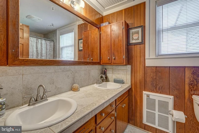 bathroom featuring a sink, visible vents, backsplash, and double vanity