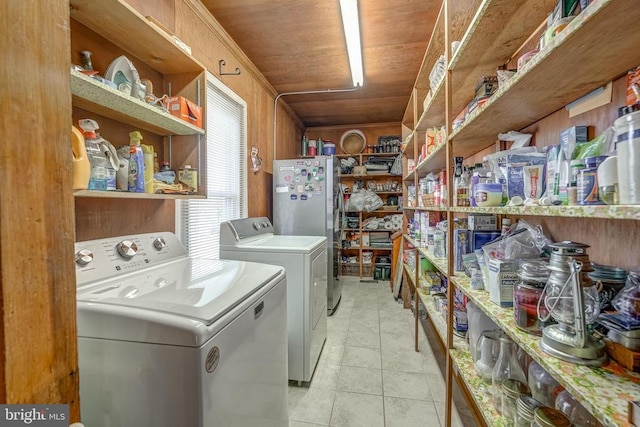 laundry room featuring light tile patterned floors, washing machine and clothes dryer, laundry area, wood ceiling, and wood walls