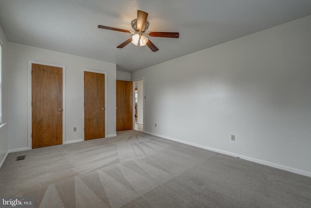 unfurnished bedroom with visible vents, multiple closets, ceiling fan, baseboards, and carpet floors