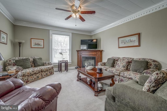 living room with a ceiling fan, baseboards, a glass covered fireplace, crown molding, and carpet flooring