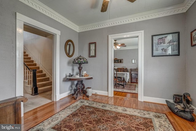 hallway with stairs, crown molding, baseboards, and wood finished floors