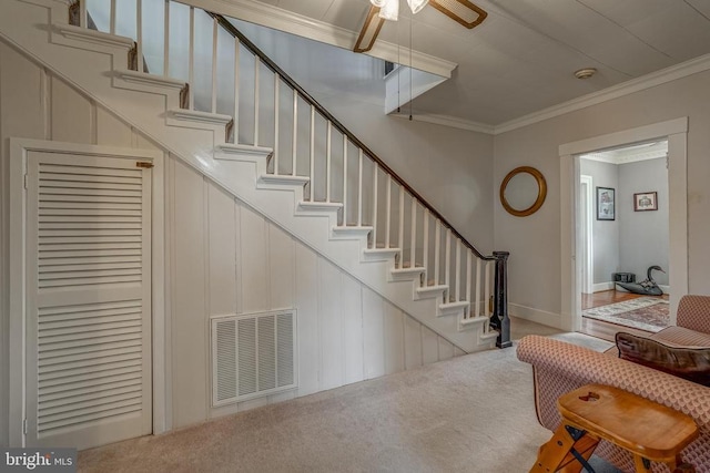 stairway featuring visible vents, a ceiling fan, crown molding, and carpet