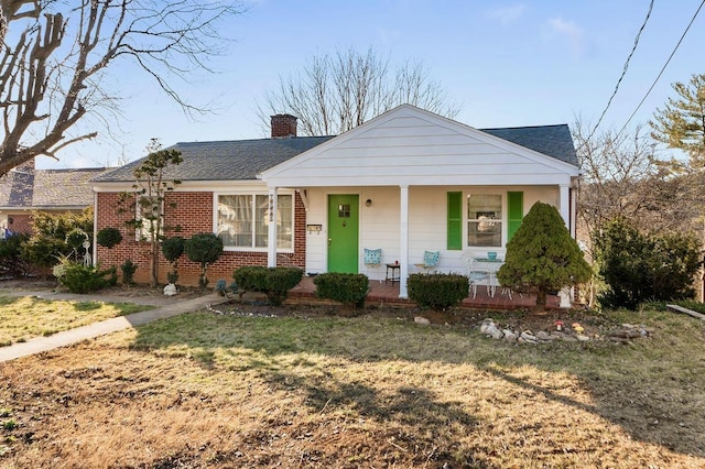 view of front of home with covered porch, roof with shingles, a chimney, and brick siding