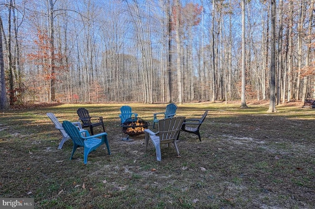 surrounding community featuring an outdoor fire pit and a wooded view