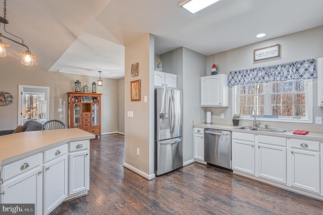 kitchen with white cabinets, dark wood finished floors, appliances with stainless steel finishes, light countertops, and a sink