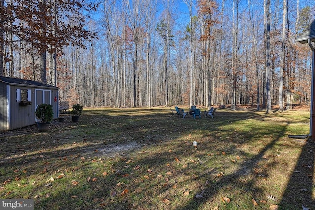 view of yard with a forest view, a storage unit, and an outdoor structure