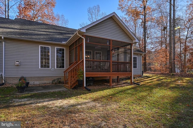 rear view of house featuring a sunroom, a shingled roof, a lawn, and a patio