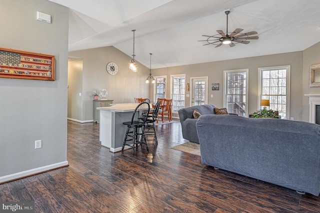 living room with vaulted ceiling, a ceiling fan, dark wood-type flooring, and a wealth of natural light