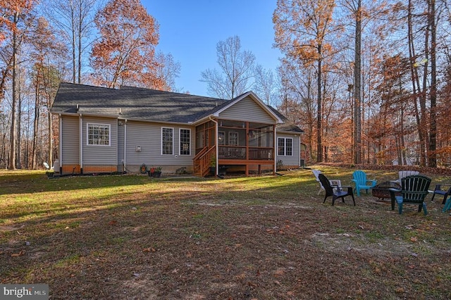 rear view of house featuring a yard, an outdoor fire pit, and a sunroom