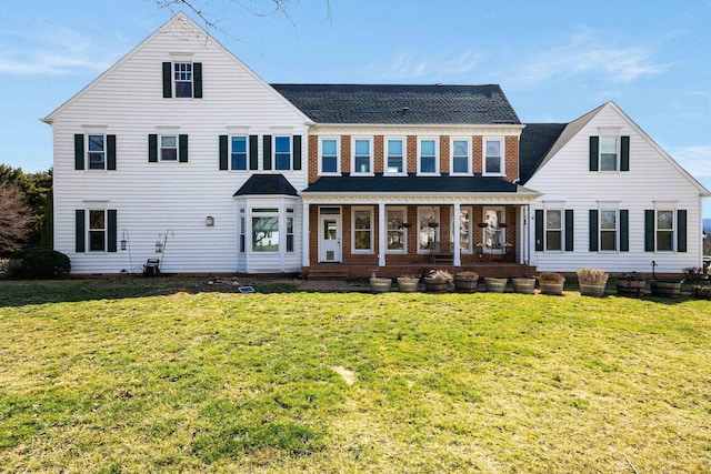 view of front of home with a front yard, covered porch, and brick siding