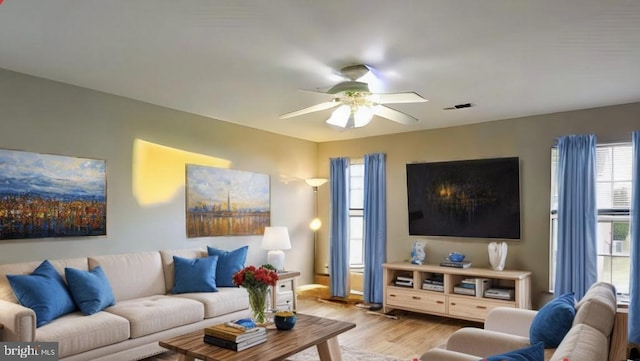 living room with visible vents, a ceiling fan, and light wood-style floors