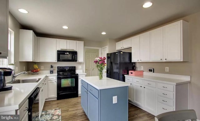 kitchen with light wood finished floors, white cabinets, black appliances, and a sink