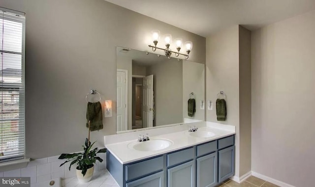 bathroom featuring tile patterned flooring, double vanity, baseboards, and a sink