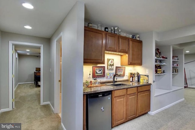 kitchen featuring light carpet, dishwasher, baseboards, and a sink