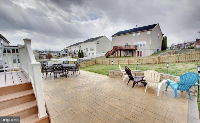 view of patio with a residential view, a wooden deck, outdoor dining area, and a fenced backyard