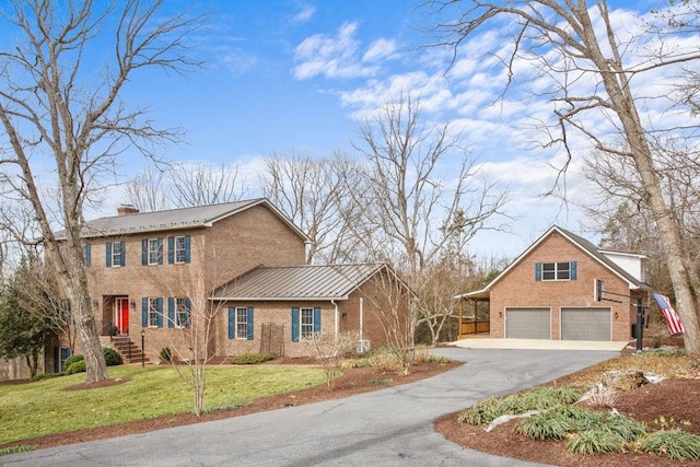 view of front facade with aphalt driveway, brick siding, a chimney, an attached garage, and a front yard