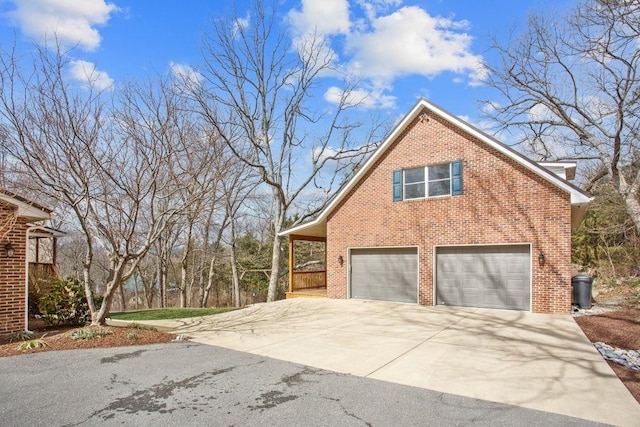 view of home's exterior featuring a garage, brick siding, and driveway