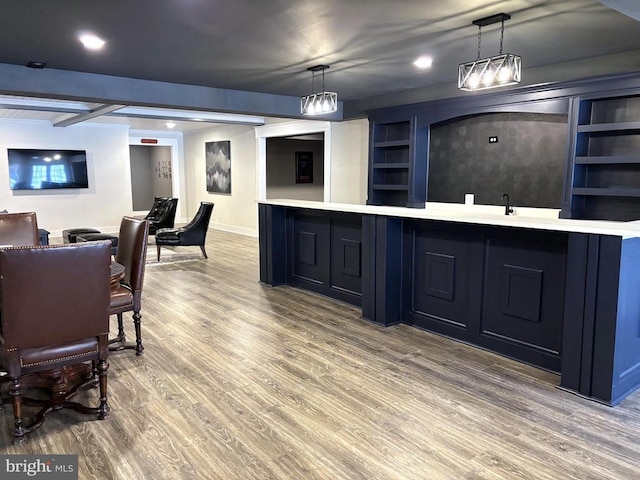 bar with hanging light fixtures, built in shelves, indoor wet bar, and wood finished floors