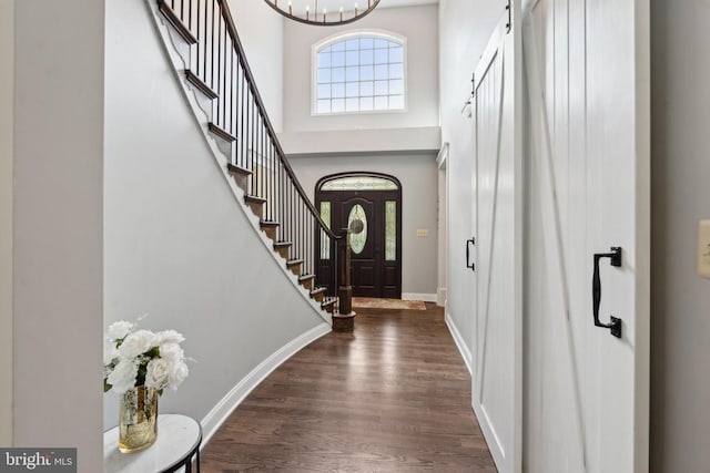 foyer featuring an inviting chandelier, dark wood-type flooring, and a high ceiling