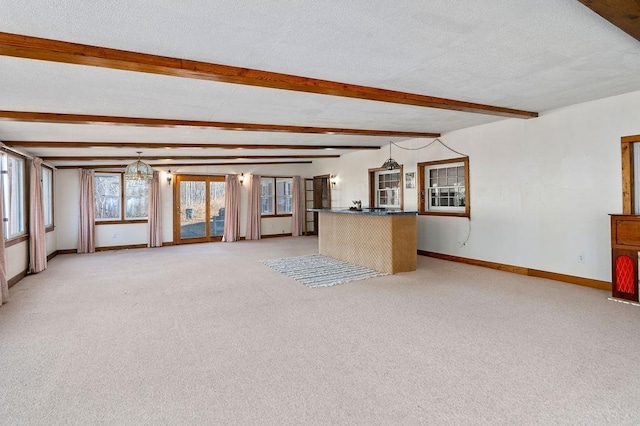 unfurnished living room with a textured ceiling, baseboards, beamed ceiling, and light colored carpet