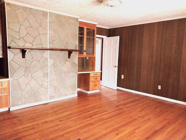 interior space featuring ornamental molding, wooden walls, and wood finished floors