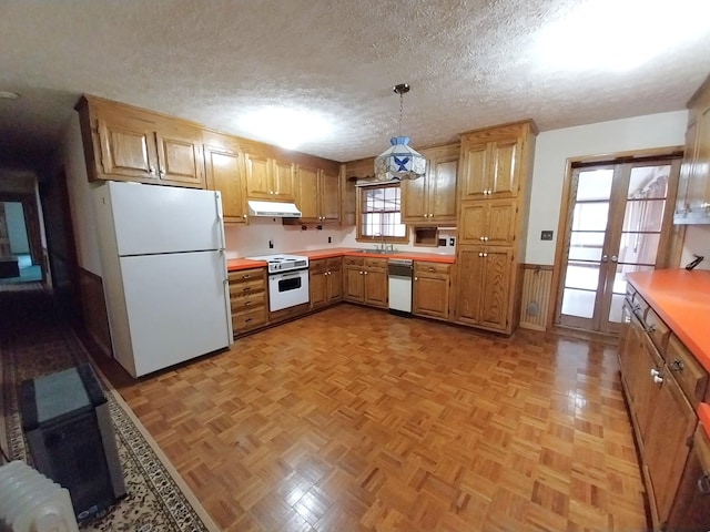 kitchen featuring under cabinet range hood, white appliances, hanging light fixtures, light countertops, and wainscoting