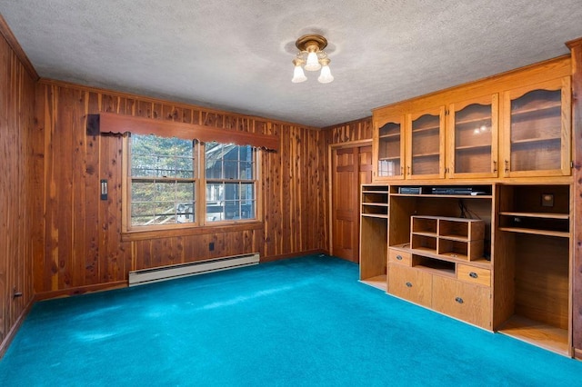 interior space with wood walls, a baseboard radiator, dark carpet, and a textured ceiling