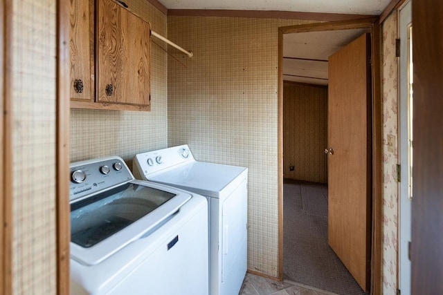 washroom with cabinet space, washer and clothes dryer, and wallpapered walls