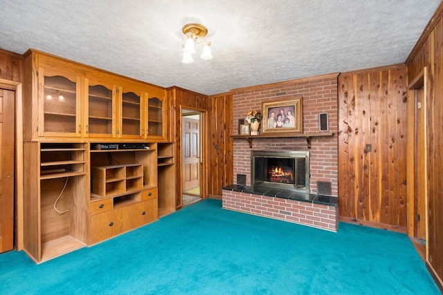 living room featuring a textured ceiling, dark carpet, wood walls, and a fireplace