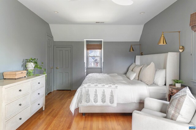 bedroom featuring visible vents, lofted ceiling, and light wood-style floors